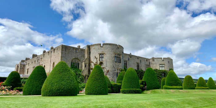 Chirk Castle in Wales with green grass, manicured hedges and white clouds in the blue sky.